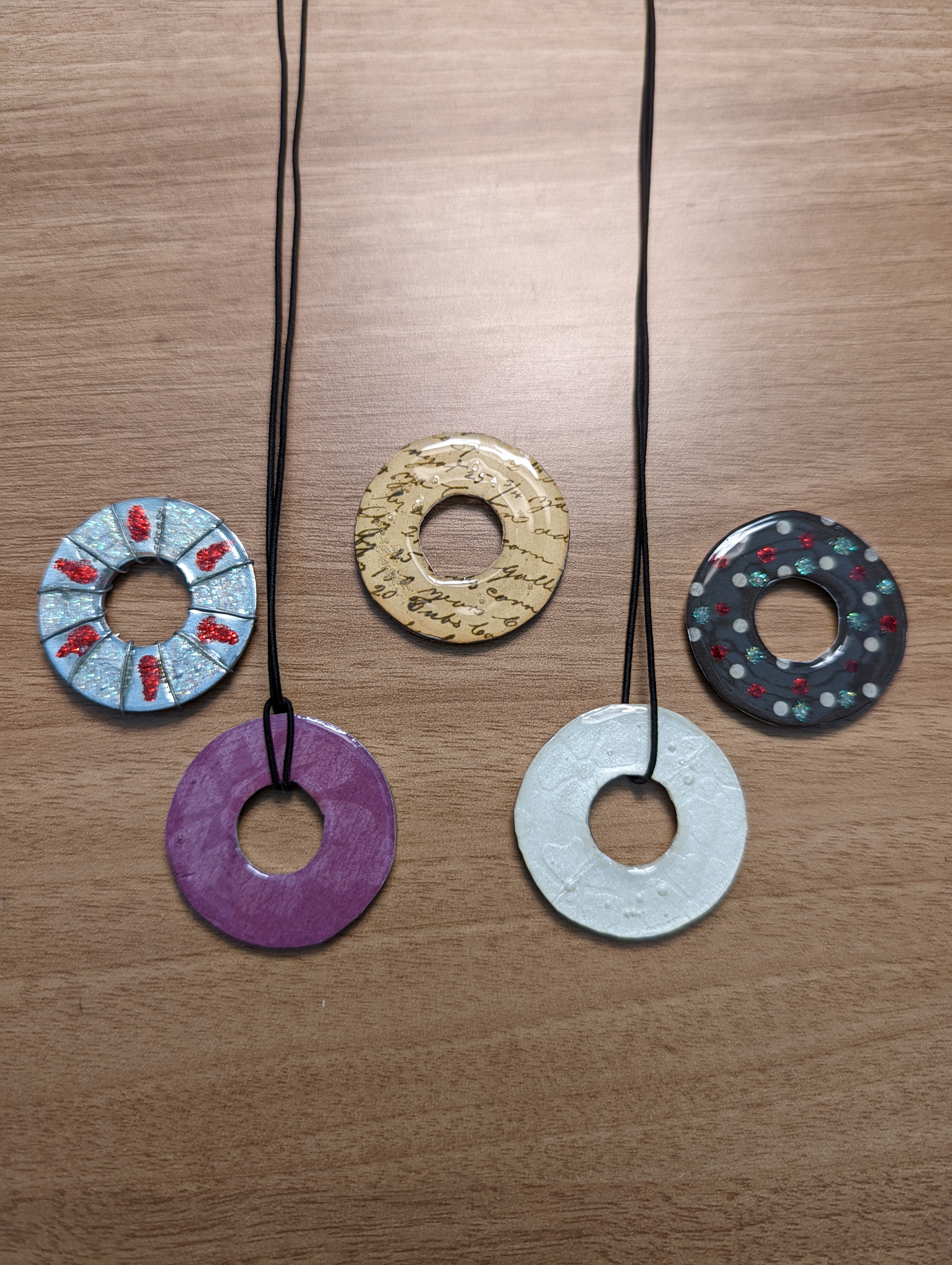 Five pendants made out of washers, two of them on necklace cords.