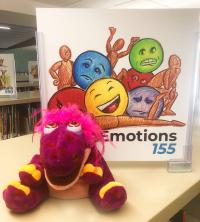 Spotty sits by the "Emotions" sign in Juvenile Nonfiction