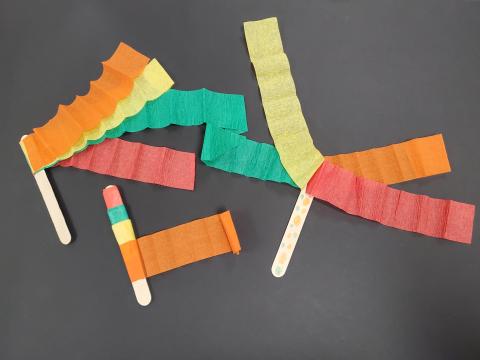 photo of three ribbon wand crafts, each is a popsicle stick with colorful streamers glued on
