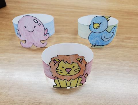 Example of paper bracelet craft. Image shows three paper bracelets, one of a lion, one of an octopus, and one of a blue bird.