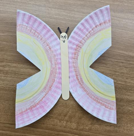 Photo of a butterfly made out of paper plates and a popsicle stick.