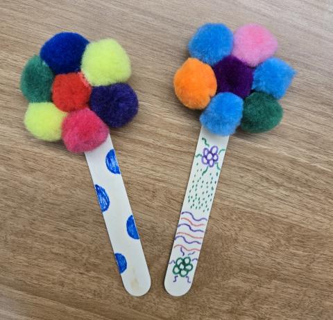 Photo of two pom pom bookmark crafts on a brown table background.
