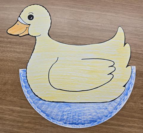 Image of a yellow duck glued to a folded paper plate colored blue.